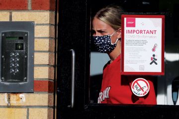 A student leaves one of the accommodation blocks with a Covid sign on the window