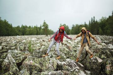 Young tourists walking down big stones while hiking
