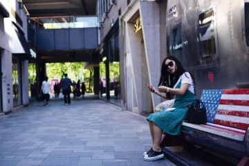 A woman sitting on an empty bench painted in a US flag in Beijing to illustrate Study abroad: US students all but absent from China
