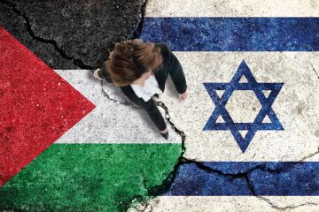 Woman walking over cracked paving made up of Palestine and Israel flags