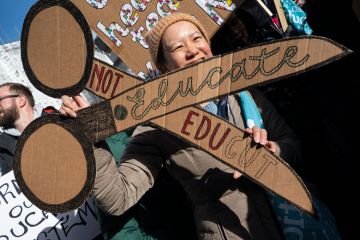 UCU member holding a cardboard banner of a pair of scissors to protest against cuts to illustrate UK sector at ‘rock bottom’ as pay dispute derails graduations