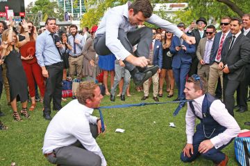 A man jumps over two men who have their ties tied together as they play a game of Limbo in Melbourne, Australia. A man jumps over two men who have their ties tied together as they play a game of Limbo in Melbourne, Australia to illustrate Australian universities ‘already near’ overseas enrolment caps