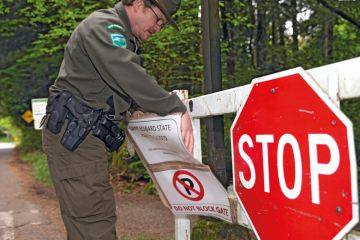 A ranger adjusts stop sign saying the park is closed in Kenmore, WA, Seattle A ranger adjusts stop sign saying the park is closed in Kenmore, WA , Seattle to illustrate US college closures could spread to public universities