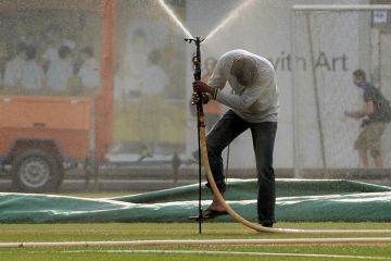 A man tries to place a water sprinkler on a field in Singapore
