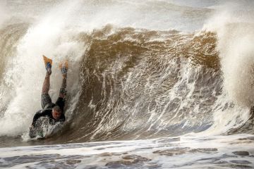 A surfer on a small board falls on a wave to illustrate Australian migration rules ‘risk international education crisis’