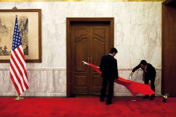 Chinese national flag placed on it's side by workers with a US national flag upright to illustrate pace of rollback of US restrictions on global science collaborations slows