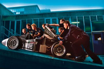 Students push a racing car up a ramp at Bath University to illustrate fostering belonging will attract students to campus