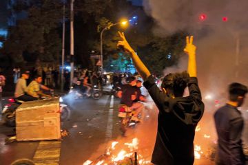 A demonstrator raising his arms and makes the victory sign during a protest for Mahsa Amini to illustrate Academics under mounting pressure to join Iranian protests
