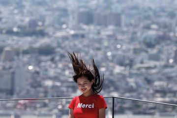 A woman poses for a picture with her hair blown upwards with the Tokyo skyline on the Shibuya Sky observation deck in Tokyo to illustrate ‘Sharp rise’ in science gender quotas at Japanese universities