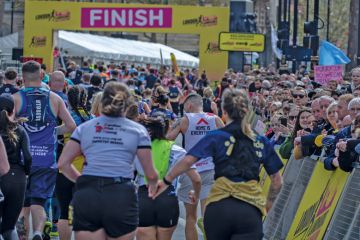 Runners holding hands approach the finish line at the London Landmarks Half Marathon 2024 to illustrate record numbers are getting clearing for university admissions