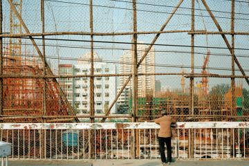 Woman looking down at construction site, Beijing, China to illustrate Chinese universities abandon or repurpose regional campuses
