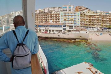 Man standing on ferry looking at Messina city skyline to illustrate Italy turns hotels into student halls to battle demographic decline