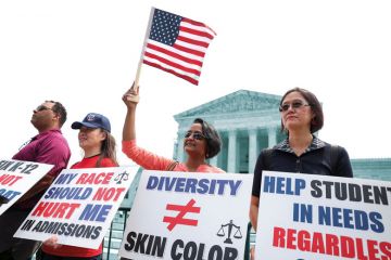 Protesters hold signs as demonstrators for and against the U.S. Supreme Court decision to strike down race-conscious student admissions programs at Harvard University and the University of North Carolina confront each other, in Washington