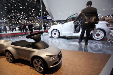 A toy car for Audi AG is seen on the company's stand with a man looking at white car in background
