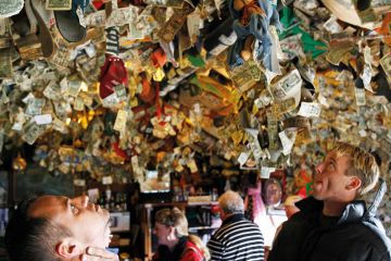 People looking up at pinned mementos left on the ceiling.