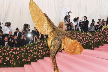  on the red carpet person wearing  huge gold sparkle angel wings