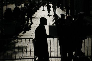 people walking with barricades and officers at the entrance 