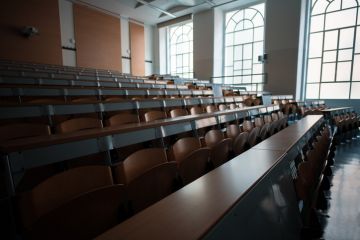 Wide angle shot of a university classroom with rows of chairs and desks