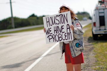 Woman holding 'Houston, we have a problem' sign Woman holding 'Houston, we have a problem' sign