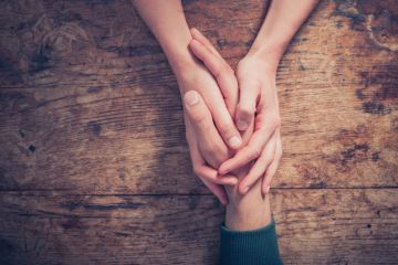 Woman holding man's hand providing support/kindness