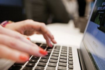 Woman typing Apple MacBook laptop Woman typing Apple MacBook laptop
