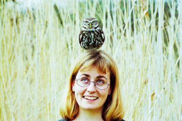 A woman with an owl balanced on her head A woman with an owl balanced on her head
