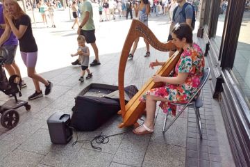 Woman busker playing the harp on O'Connell Street, Dublin city centre Woman busker playing the harp on O'Connell Street, Dublin city centre