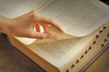 Woman's hand turning dictionary pages