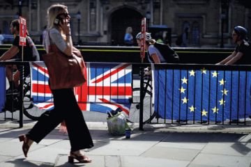 Woman walking past UK and EU flags