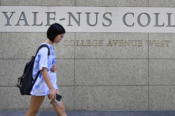 A student walking past signage for the Yale-NUS College in Singapore A student walking past signage for the Yale-NUS College in Singapore