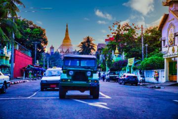 Yangon, Myanmar - December 02 2012  a military jeep on street of Yangon Myanmar and a Pagoda in the background