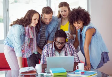 A group of students gathered around a laptop