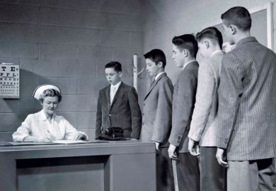 A nurse sitting at a table with a queue of people waiting to speak to her
