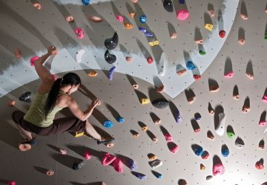A woman scaling a climbing wall