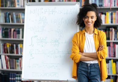 A black academic in front of a white board