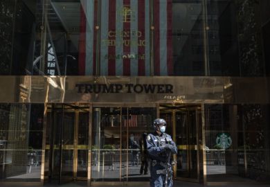 A counter-terrorism officer wearing a face mask stands at the entrance of Trump Tower