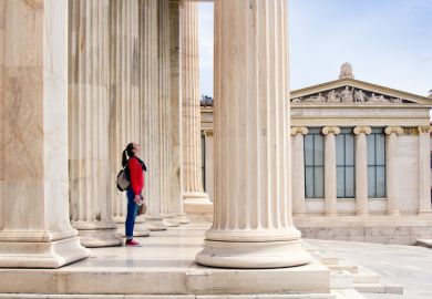 A girl looks up at the ceiling, under the columns of the Athenian Academy