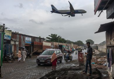 An aeroplane flies over slums in Mumbai