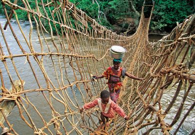 African woman and child crossing rope bridge