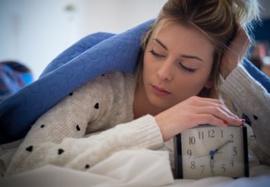 Alarm clock A young woman turns off an alarm clock