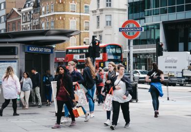People walking outside a busy Aldgate East tube station, London