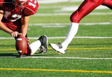 American football player preparing to kick ball American football player preparing to kick ball