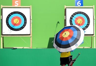  An archer holding an umbrella with a target design checks the target during the first day of an archery test event. To illustrate challenging new UKRI targets for industry-funded research.