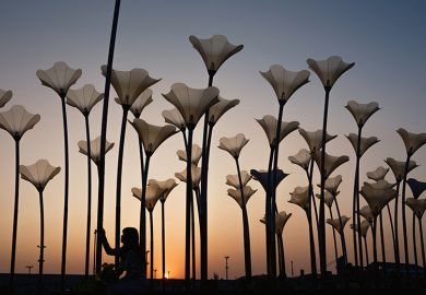 A woman prepares to take selfies with flower sculptures at sunset at the Pier-2 Art Center in Kaohsiung on 10 January, 2024. To illustrate that Asian universities are rising in the rankings in arts and humanities subjects.
