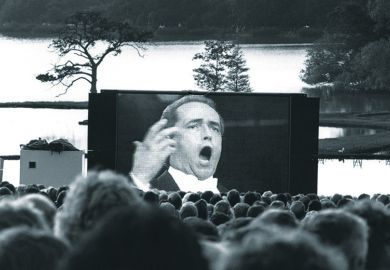 Audience watching opera singer on large screen