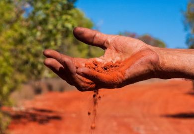 Red Australian earth slips through Indigenous Australian’s fingers Red Australian earth slips through Indigenous Australian’s fingers