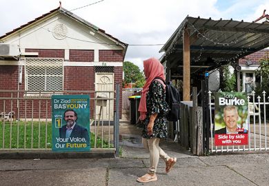 A woman walks past campaign signs depicting candidates in Lakemba, Australia, 12 March 2025. 