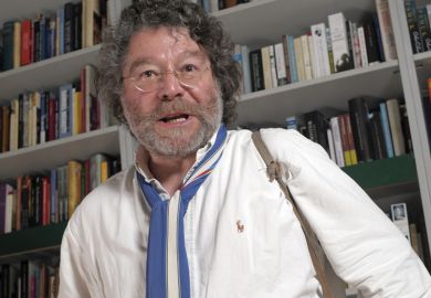 Author Craig Raine standing in front of bookcase