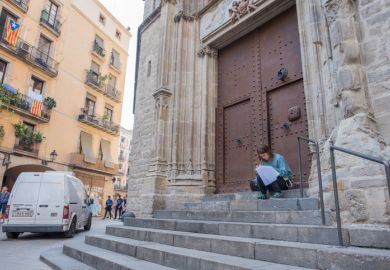 Barcelona, Spain, Oct. 12, 2017 A young woman student stops to study on the back steps of the Basilica Santa Maria Del Mar, a beautiful Gothic cathtedral in the El Born neighborhood.