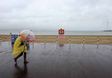 Person walking in the rain on beach in Weymouth
